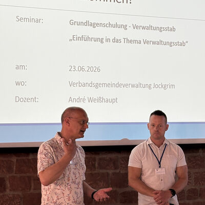 Man sieht B&uuml;rgermeister Karl Dieter W&uuml;nstel und Dozent Andr&eacute; Wei&szlig;haupt vor der Pr&auml;sentation stehen.