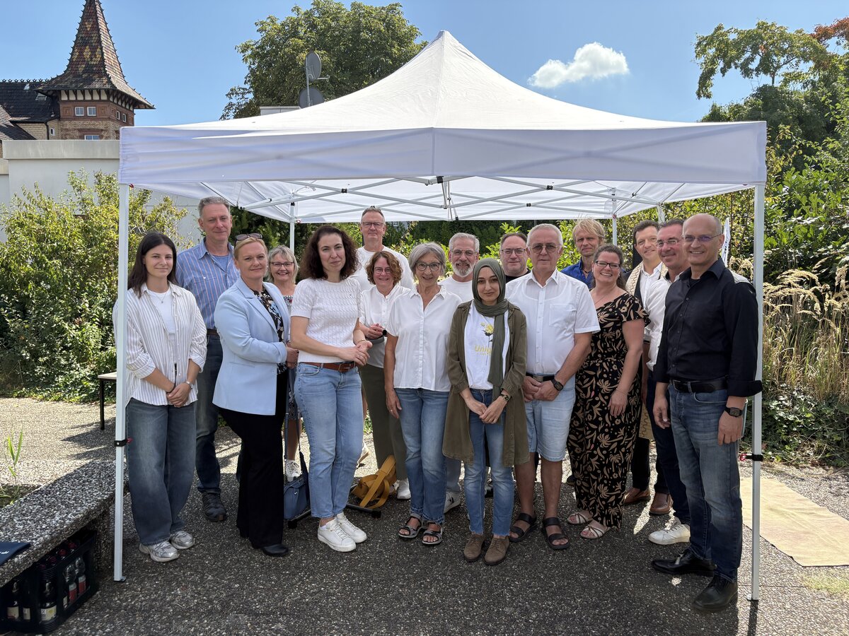Die Gruppe steht unter einem Baldachin, im Hintergrund die Spitze des Rathauses der Ortsgemeinde Jockgrim
