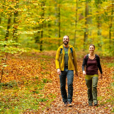 Bild vergrößern: Mann und Frau wandern auf dem Otterbachbruch-Wanderweg im Herbst