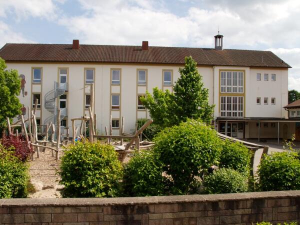 Bild vergr&ouml;&szlig;ern: St. Wendelinus Grunschule Hatzenb&uuml;hl, Au&szlig;enansicht mit Spielplatz im Vordergrund