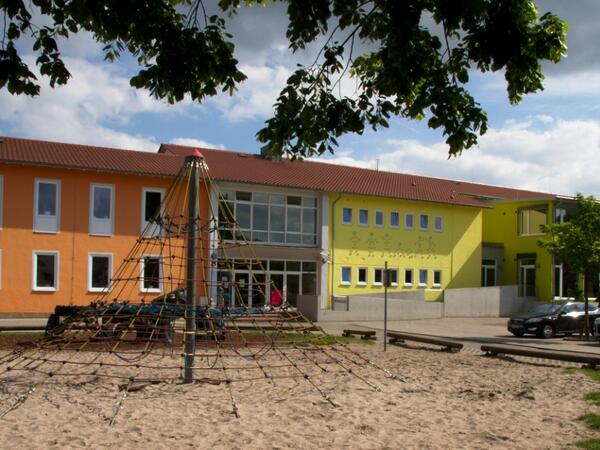 Bild vergr&ouml;&szlig;ern: Grundschule An der R&ouml;merstra&szlig;e Rheinzabern, Au&szlig;enansicht mit Spielplatz im Vordergrund.